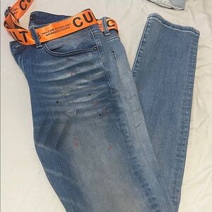 Cult of Individuality Distressed Blue Jeans with Bold Orange Belt